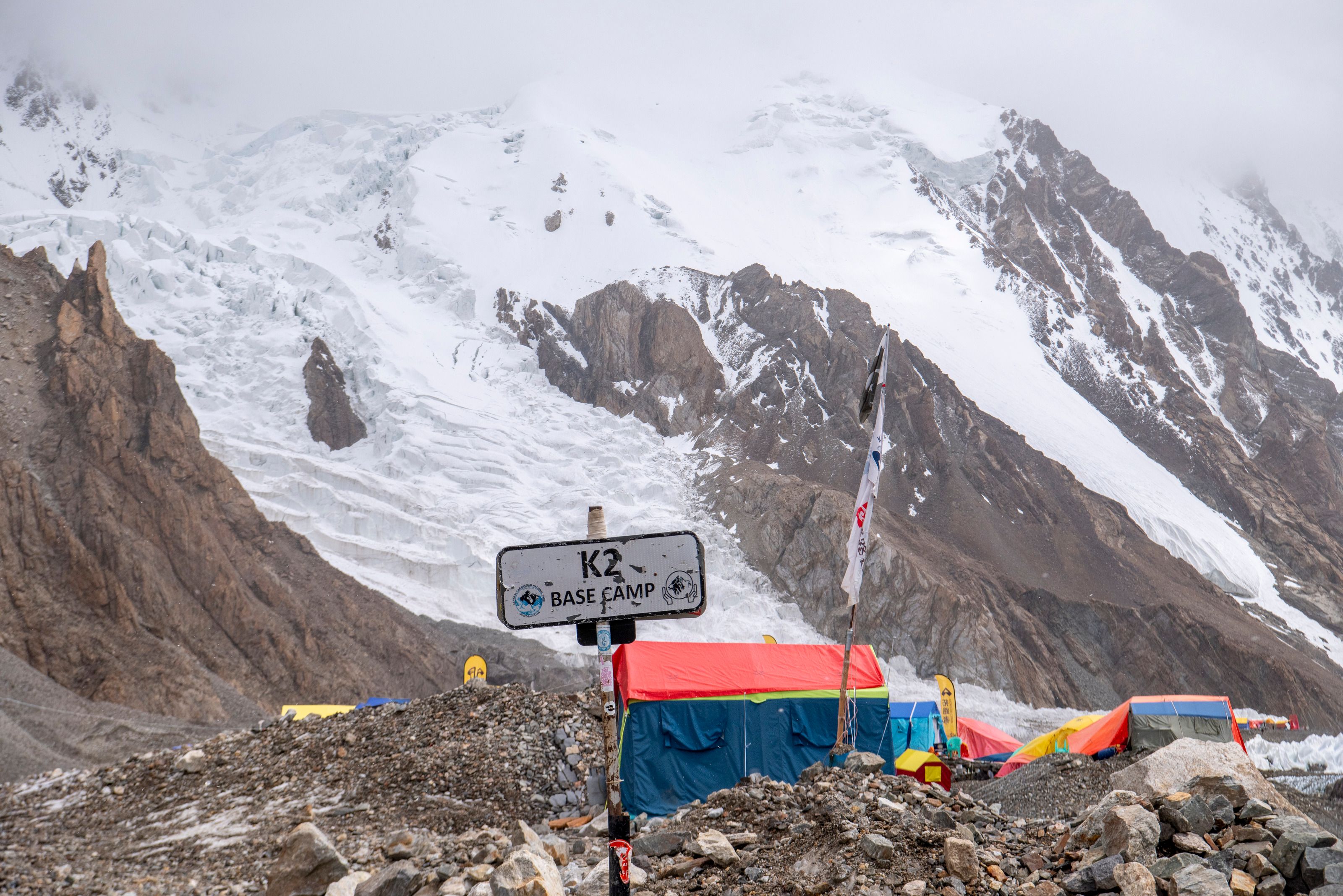 Указатель K2 Base Camp и палатки у подножия заснеженных склонов